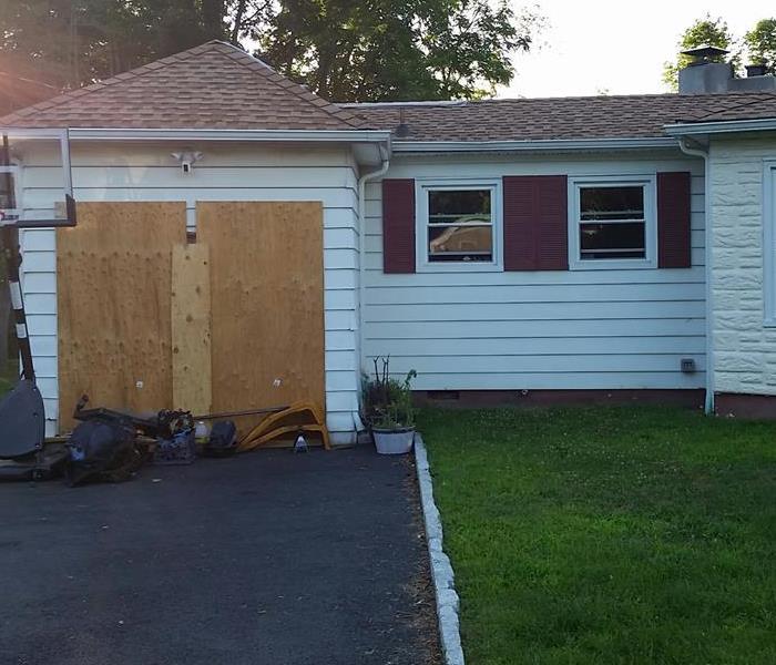 A home with an attached garage that is boarded up