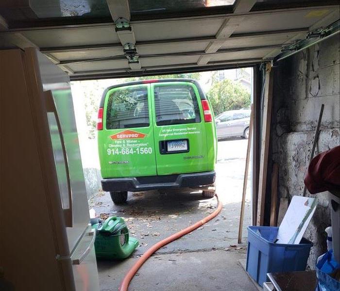 SERVPRO van parked in a driveway with an open garage door.